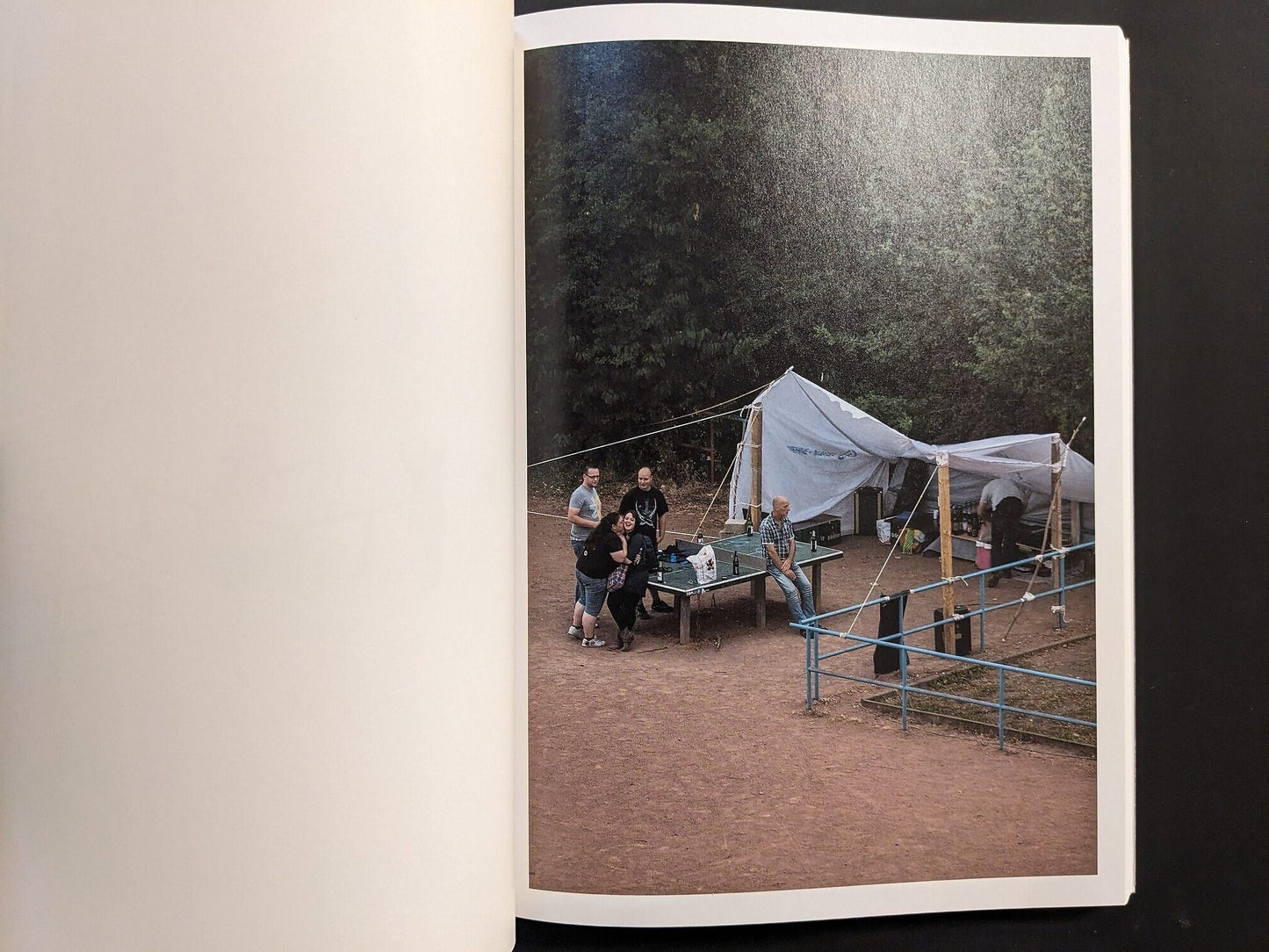 Photograph of people gathered around the table under a makeshift tent.