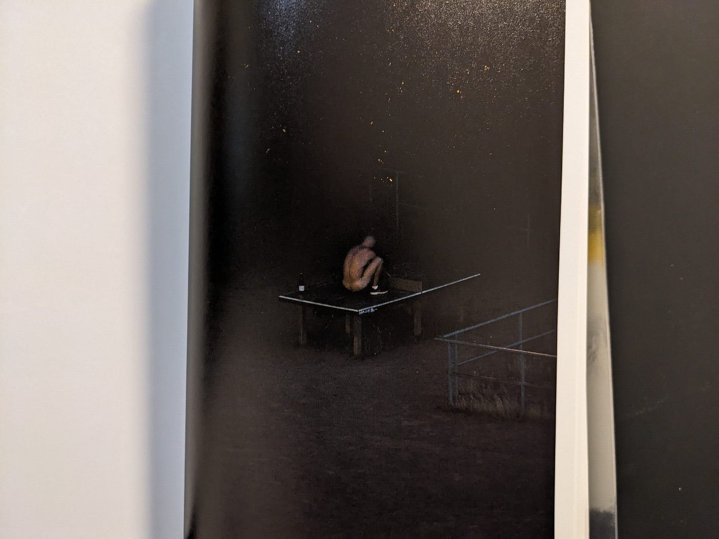 Photograph of a solitary figure sitting at the table at night.
