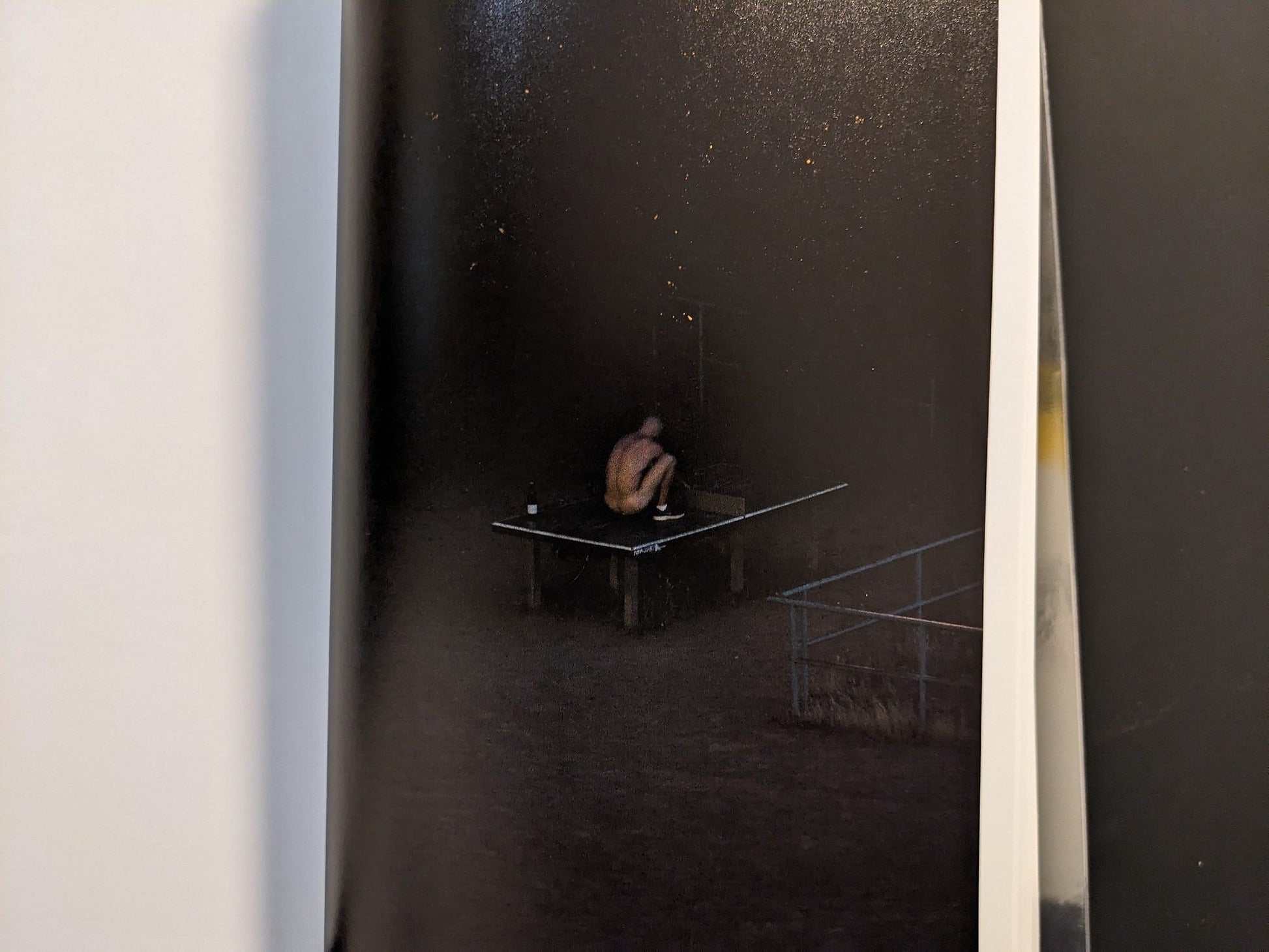 Photograph of a solitary figure sitting at the table at night.