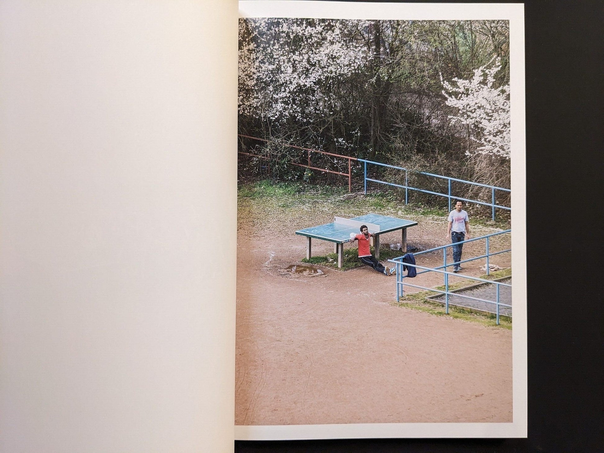 Photograph of two figures near the table under blooming spring trees.
