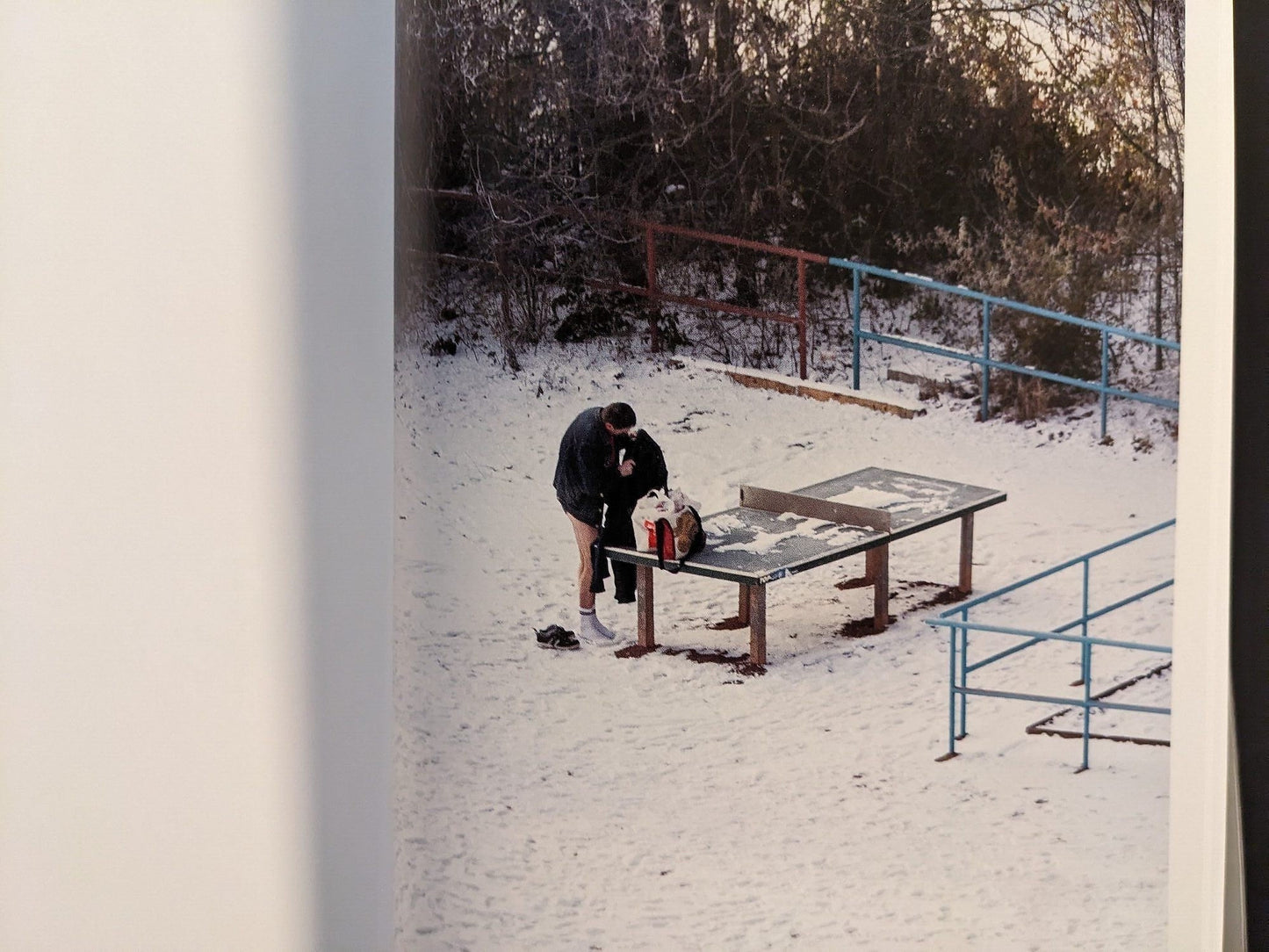 Photograph of a person near a ping-pong table in snow-covered surroundings.