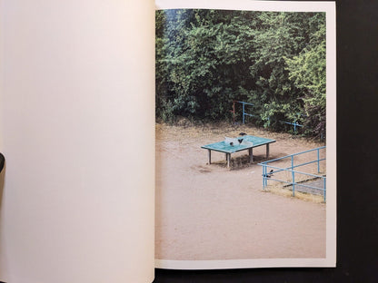 Photograph from TTP by Hayahisa Tomiyasu showing an empty ping pong table surrounded by greenery.