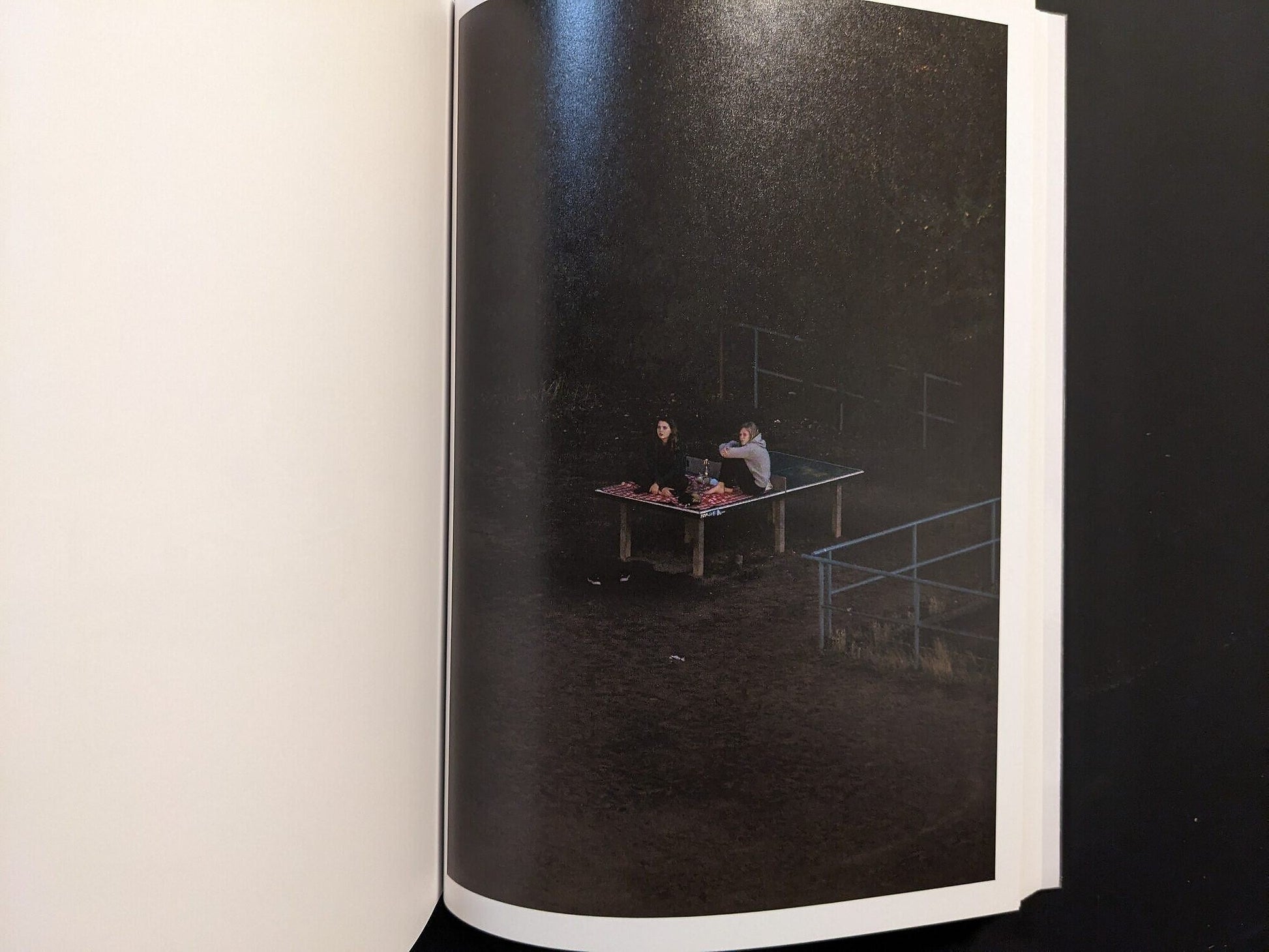 Photograph from TTP by Hayahisa Tomiyasu showing two figures lying on a table in the dark surroundings.