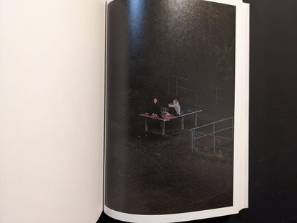 Photograph from TTP by Hayahisa Tomiyasu showing two figures lying on a table in the dark surroundings.