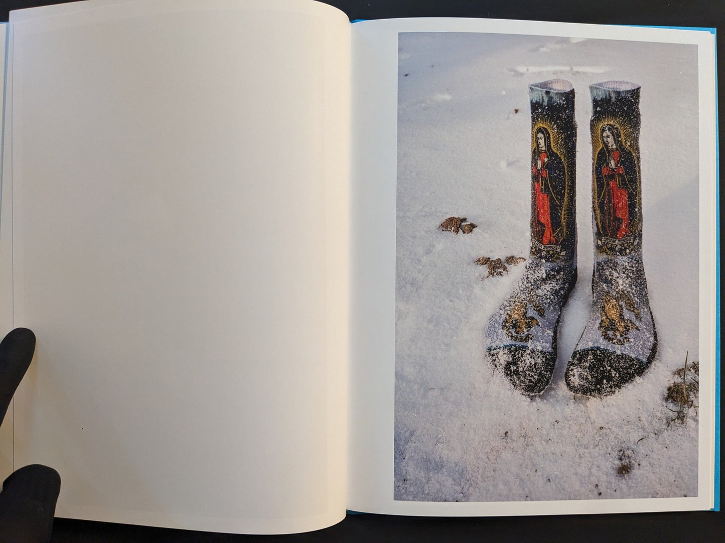 Open spread from ¥€$U$ (JESUS) showing socks printed with Virgin Mary images lying in snow.