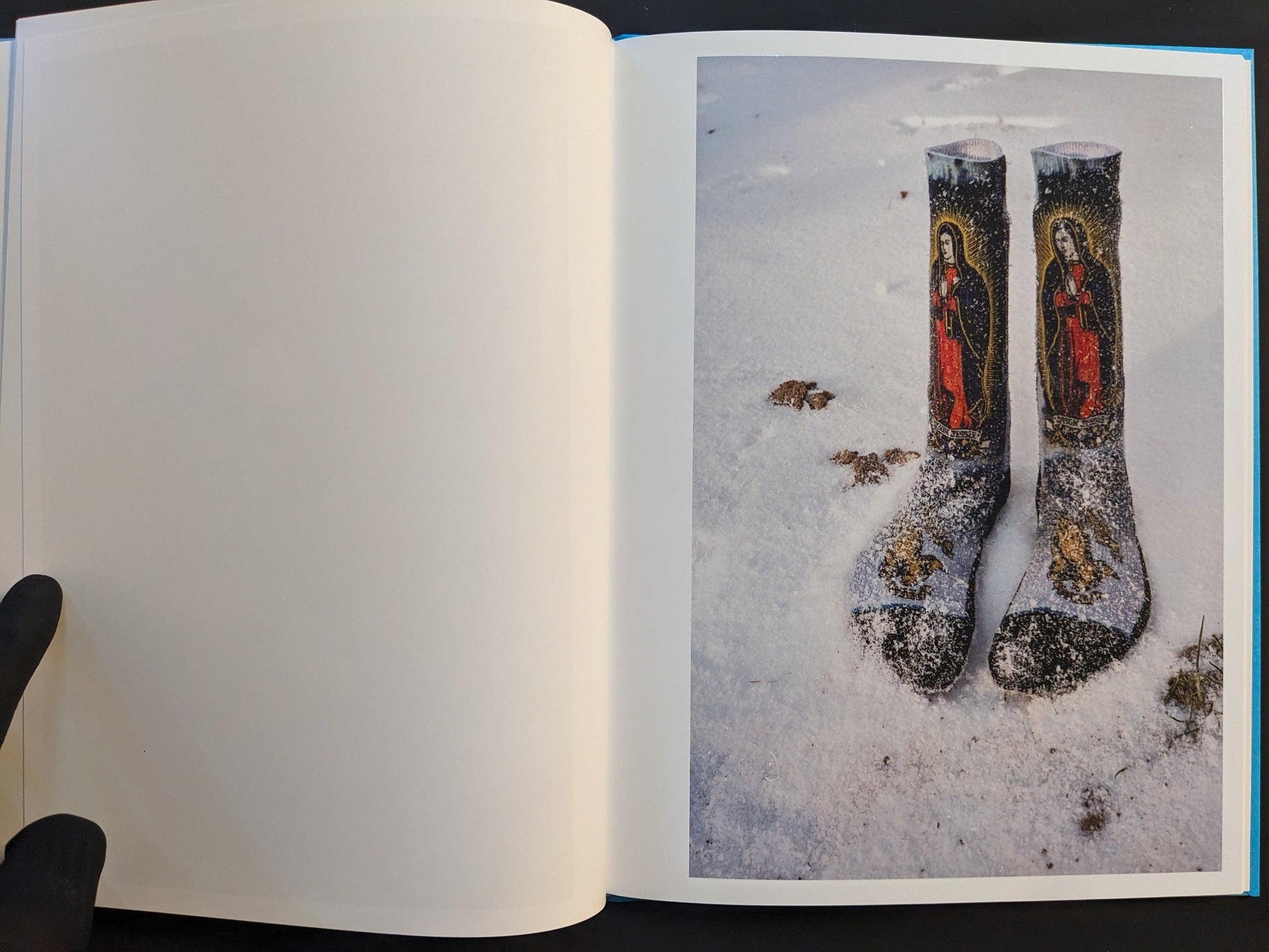Open spread from ¥€$U$ (JESUS) showing socks printed with Virgin Mary images lying in snow.