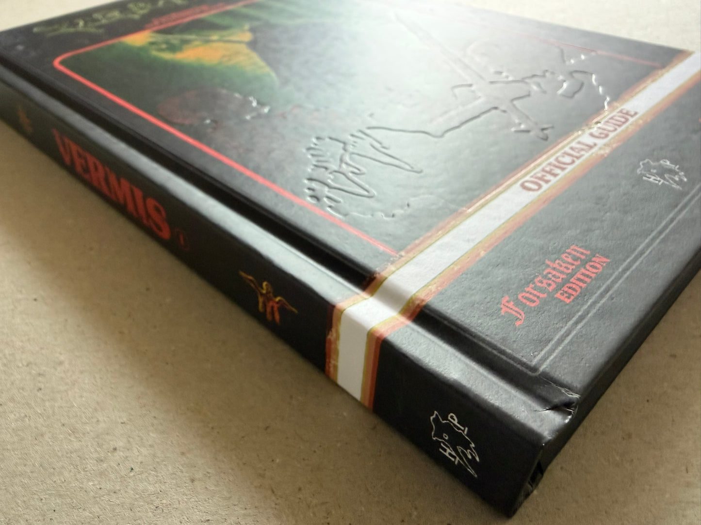 Angled close view of the embossed hardcover, showing the raised cover design and the white and red band across the front.