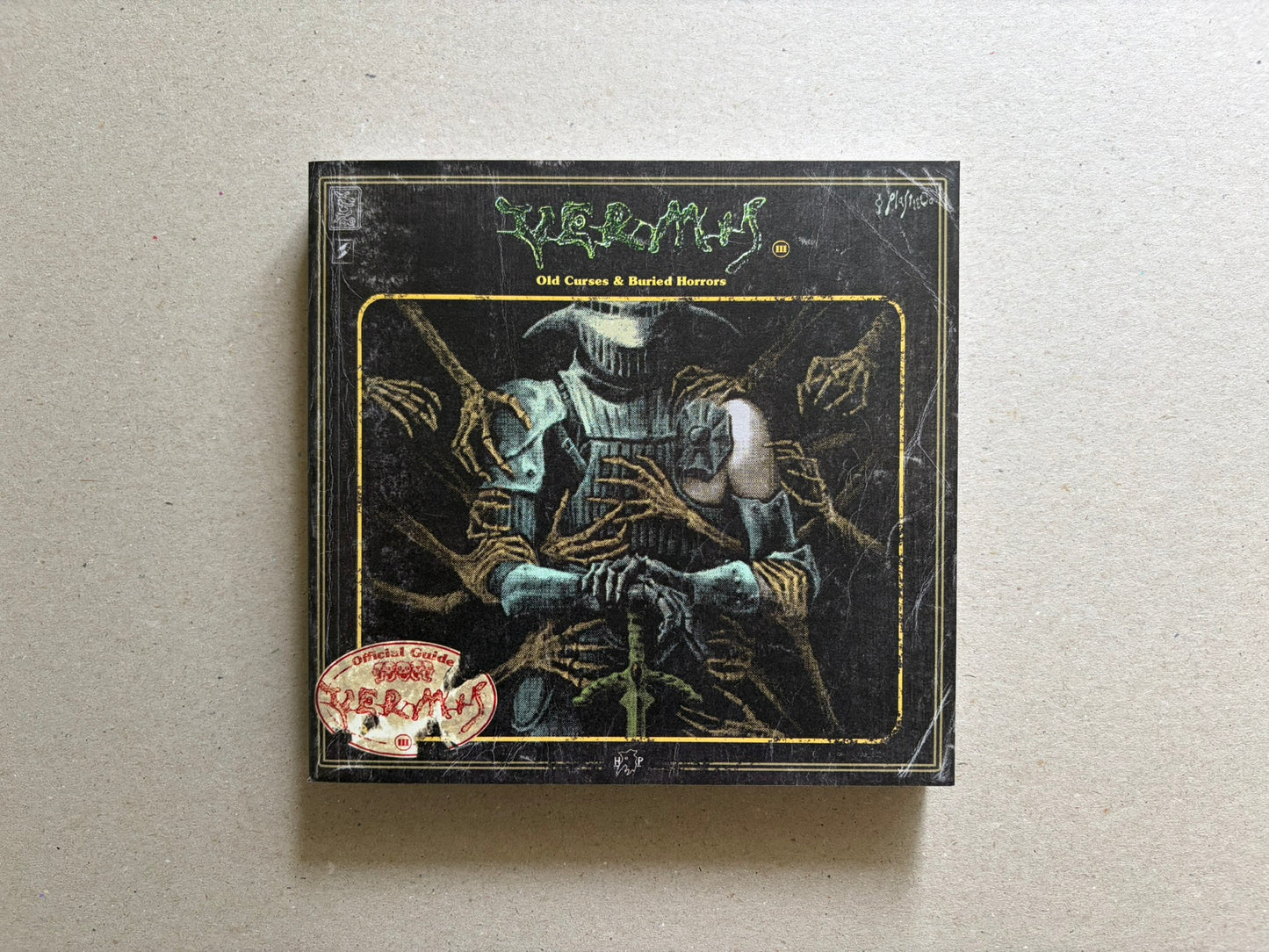 Vermis III cover on a light tabletop, showing the black front cover with the title and central armored figure illustration.