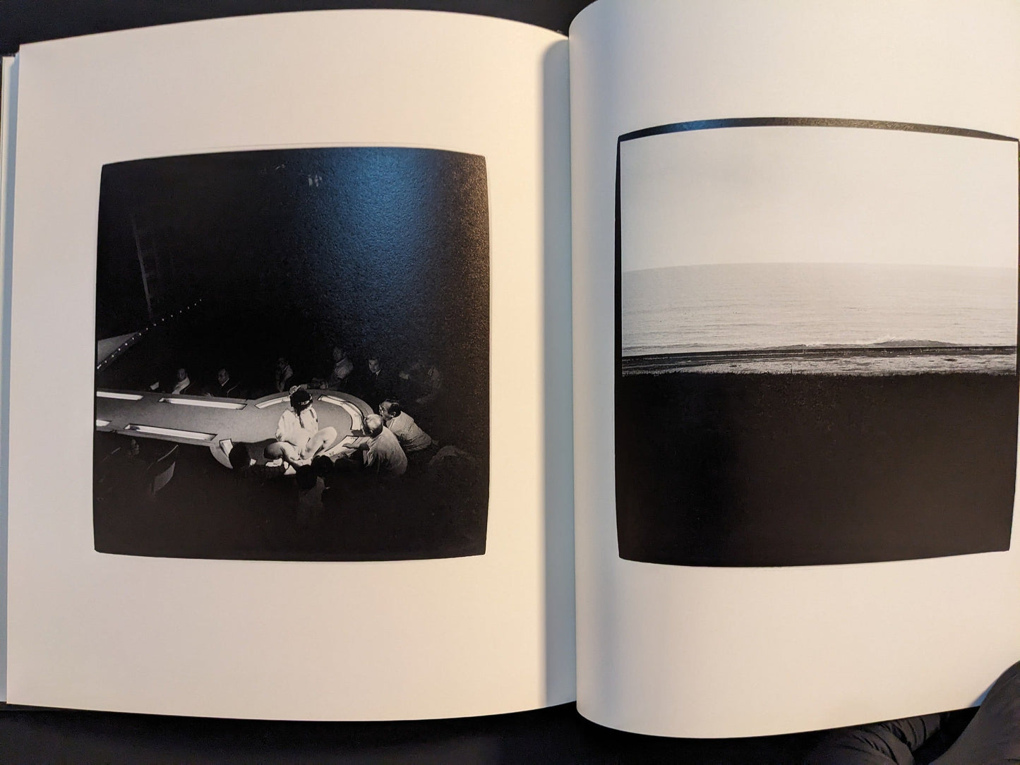 Spread with a crowded casino table under bright strip lights above and a quiet seascape below.