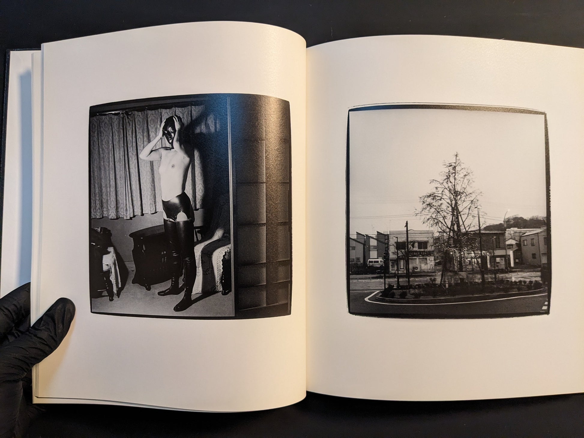 Spread with a partially dressed figure in a domestic interior and a small town roundabout with a bare tree.