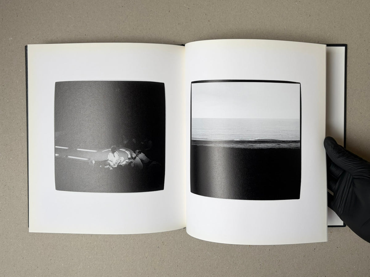 Open photobook spread from Walk while ye have the light by Yoshiichi Hara, showing two black-and-white photographs: a small group seated on a dark road at left and a seascape at right.