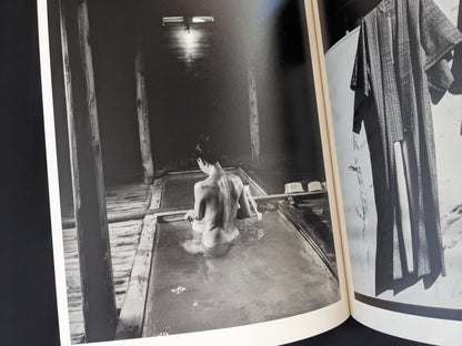 Black and white photograph of a person bathing in wooden interior from Wandering Dog