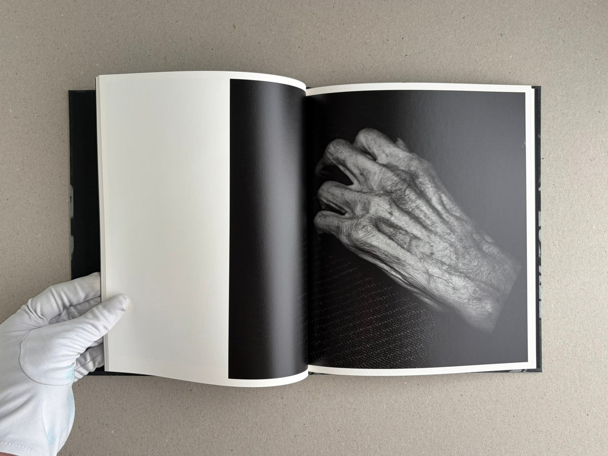 Open copy of Wandering Dog by Mai Nakama showing a blank left page and a black-and-white photograph of a hand on the right page