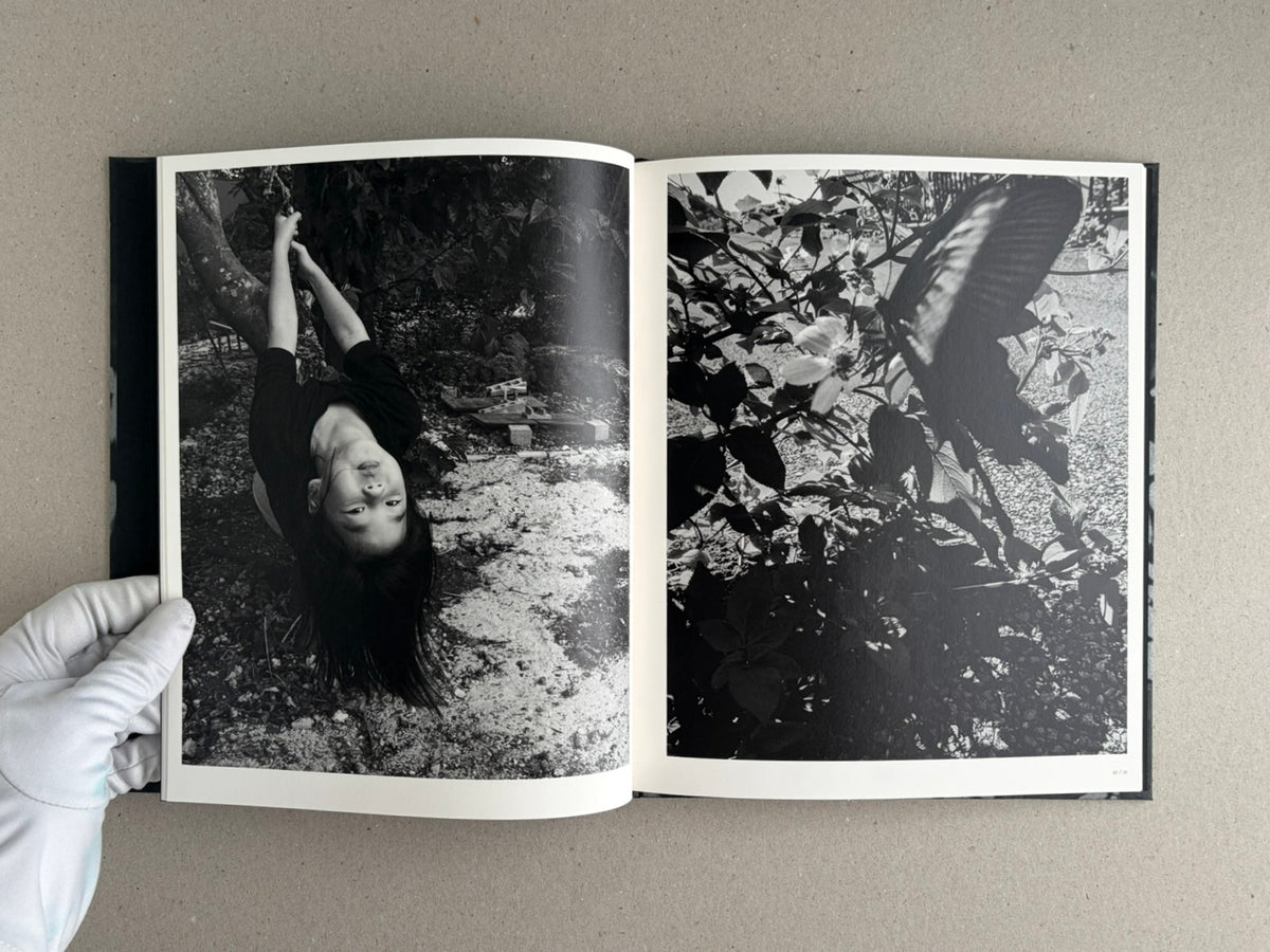 Wandering Dog by Mai Nakama, open photobook spread with a black-and-white portrait on the left and dense foliage on the right.