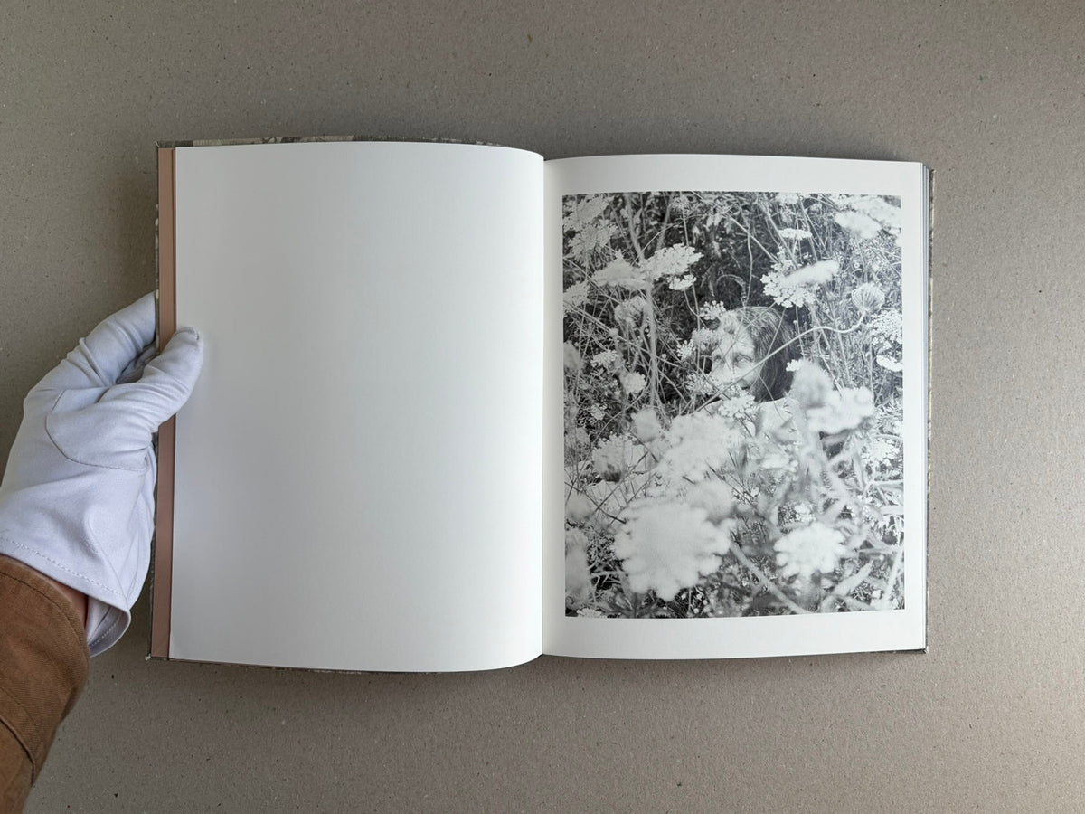 Open photobook spread from What the Rain Might Bring by Dylan Hausthor, showing a blank left page and a black-and-white photograph on the right page.