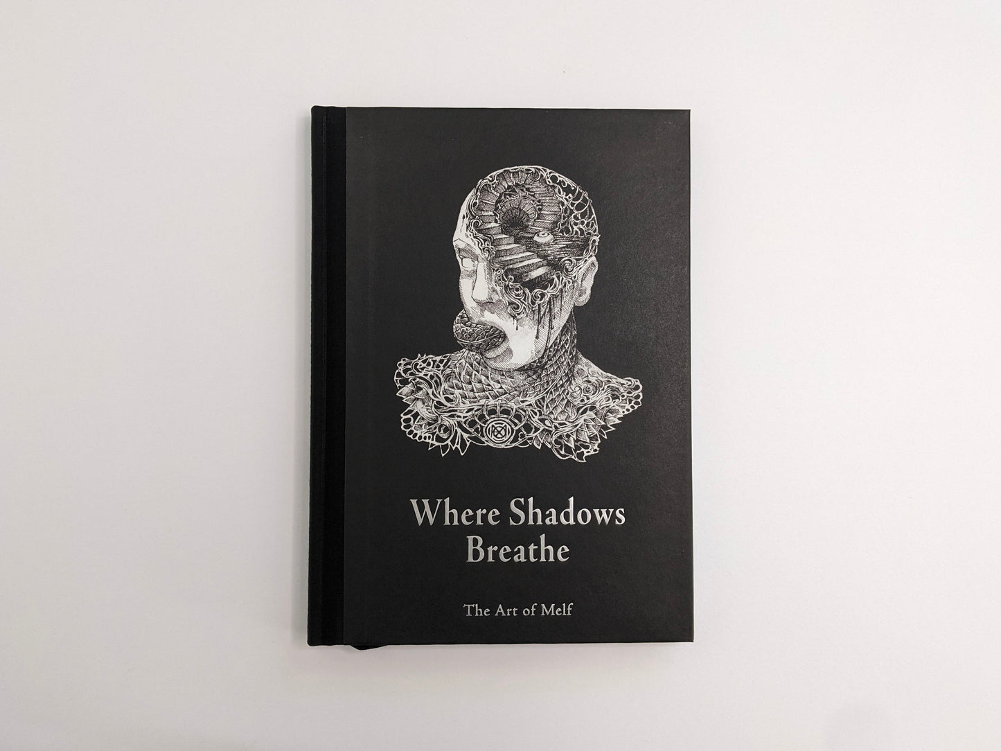 Front cover of Where Shadows Breathe: The Art of Melf, black cloth-bound hardcover with an illustrated head and title.
