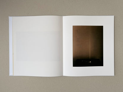 Open photobook spread from Yamamoto Masao, showing a mostly blank left page and a right page with a single dark-toned image.