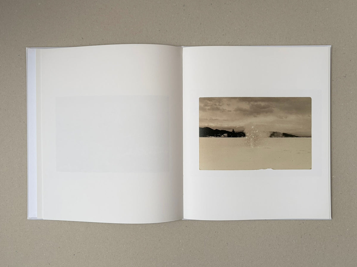 Open Yamamoto Masao photobook showing a tipped-on landscape image on the right-hand page and a blank left-hand page.