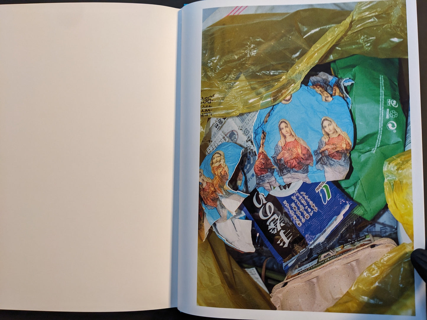 Inside page from “¥€$U$ (JESUS)” featuring torn wrappers with repeated Virgin Mary prints lying in a trash bag with other rubbish.