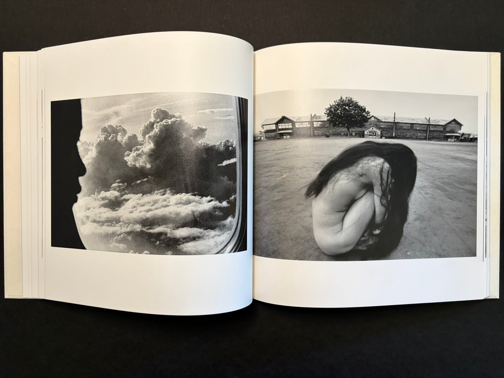 Open spread with a cloud reflection in an airplane window on the left and a crouched figure by the sea on the right.